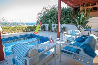 a patio with a bed and a swimming pool at Protaras Artisan Seafront Villa in Protaras