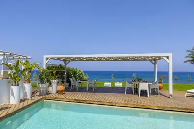 a villa with a swimming pool and a table and chairs at Beachfront Dream Villa in Protaras