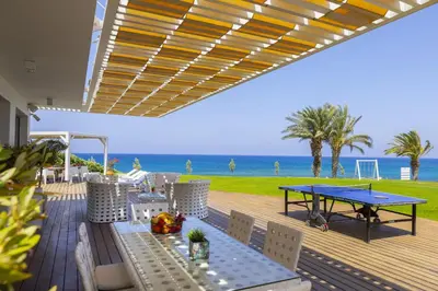 a deck with a ping pong table and the beach at Beachfront Dream Villa in Protaras