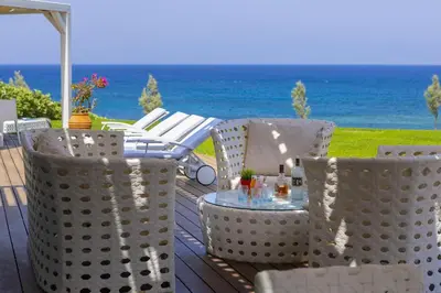 a table and chairs on a deck with the ocean at Beachfront Dream Villa in Protaras