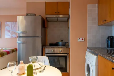 a kitchen with a refrigerator and a table with wine glasses at Johny's Spot in Larnaca in Larnaka
