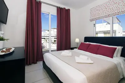 a bedroom with a large bed with red curtains at Villa Nissinia - Nissi Beach Area in Ayia Napa