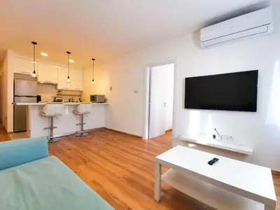 a living room with a couch and a tv on a wall at CityCenter Boutique Apartment in Larnaka