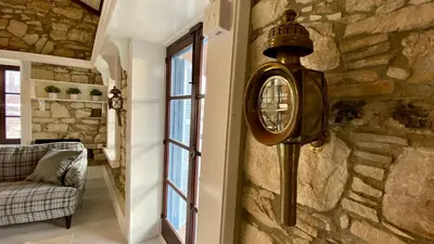 a clock on a stone wall next to a window at Leonys House by TrulyCyprus in Doros