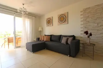 a living room with a black couch and a table at NISSI 3 VIEW HOLIDAY 2 BEDROOM APARTMENT in Ayia Napa