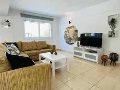a living room with a couch and a tv at Serena's 2-BR Apartment in Larnaca in Larnaka