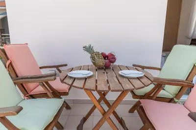 a wooden table with a pineapple and plates and chairs at Mythical Sands Resort & Spa, Evilion Apartment in Paralimni