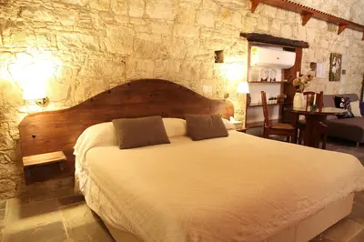 a bedroom with a large bed in a stone wall at Agrovino Lofou in Lofou