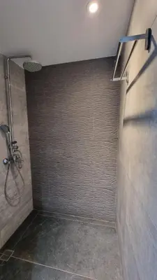 a bathroom with a shower with a tile wall at Nagia’s Apartment in Kakopetria