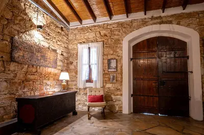 a room with a stone wall with a wooden door at Oinoessa Traditional Boutique Guest Houses in Lofou