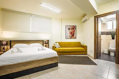 a bedroom with a bed and a yellow couch at Appartments in the historic center near beach in Limassol