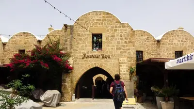 a woman walking past a stone building with a doorway at Antonakis 501 in Limassol