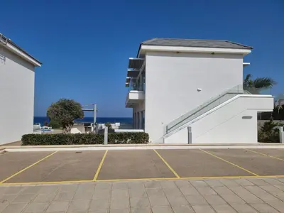 a parking lot in front of a white building at Ocean Suites Luxury Apartments in Protaras