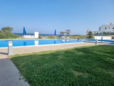 a large swimming pool with a grassy area next to at Ocean Suites Luxury Apartments in Protaras