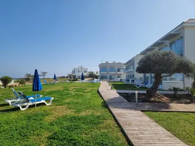 a lawn with chairs and an umbrella and a building at Ocean Suites Luxury Apartments in Protaras