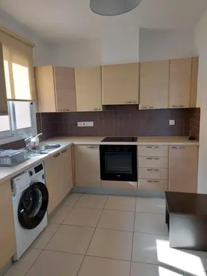 a kitchen with wooden cabinets and a washer and dryer at Pyla Palms Resort - 1 bedroom in Pyla