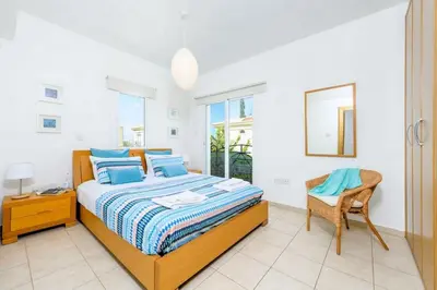a bedroom with a bed and a chair and a window at Protaras Villa Athamas Blue in Protaras