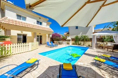 a villa with a swimming pool with chairs and an umbrella at Protaras Villa Athamas Blue in Protaras