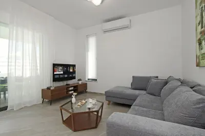 a living room with a gray couch and a tv at Villa Queen Valeria in Protaras