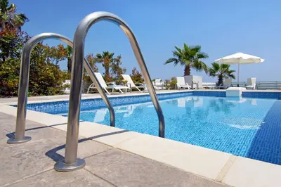 a swimming pool with metal hand rails next to a swimming pool at Villa Aphrodisia - Seafront in Ayia Napa