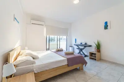 a bedroom with a large bed and a desk at Fanta Sea Apartment in Larnaka