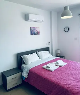 a bedroom with a large bed with a pink blanket at Cyprus Penelope in Larnaka
