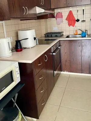 a kitchen with wooden cabinets and a counter with a microwave at Cyprus Penelope in Larnaka