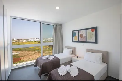 two beds in a hotel room with a window at Vie Bleu 3 Bedroom Villas in Protaras