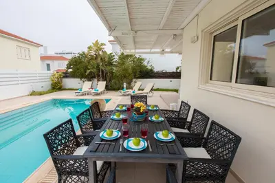 a table with plates of food on it next to a pool at Pernera Holiday Villa 588 in Paralimni