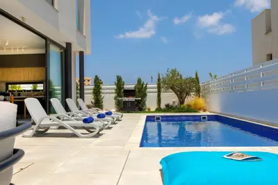 a pool with lounge chairs and a swimming pool at Protaras Almaria Villa 16 in Protaras