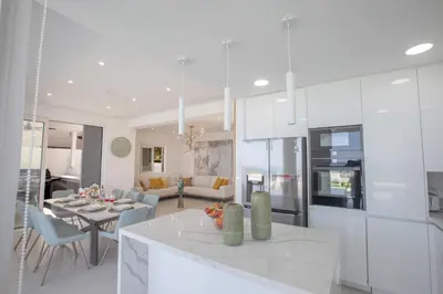 a white kitchen and living room with a table at Artizan Seafront Villa 5 in Protaras
