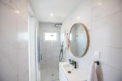 a white bathroom with a sink and a mirror at Artizan Seafront Villa 5 in Protaras