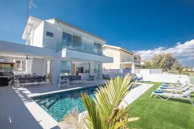 a white house with a swimming pool and a yard at Artizan Seafront Villa 5 in Protaras