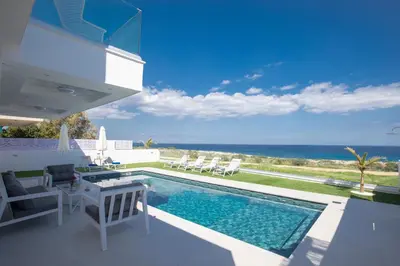 a villa with a swimming pool and the ocean at Artizan Seafront Villa 5 in Protaras