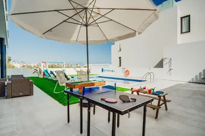 a room with a table with an umbrella and a pool at SunnyVillas 4BR New Villa Private Pool in Pernera in Protaras
