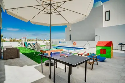 a patio with a ping pong table and an umbrella at SunnyVillas 4BR New Villa Private Pool in Pernera in Protaras