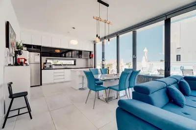 a kitchen and living room with a blue couch and chairs at SunnyVillas 4BR New Villa Private Pool in Pernera in Protaras