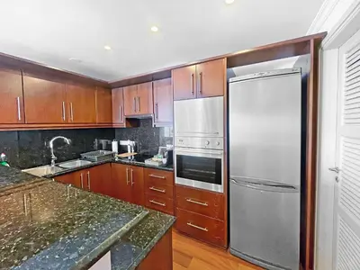 a kitchen with wooden cabinets and a stainless steel refrigerator at 180° SEAVIEW Apt. right on famous beach promenade in Larnaka