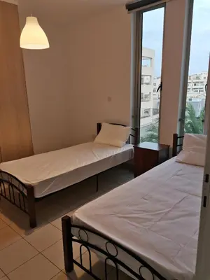 two beds in a room with a window at City Flats 308 in Larnaka