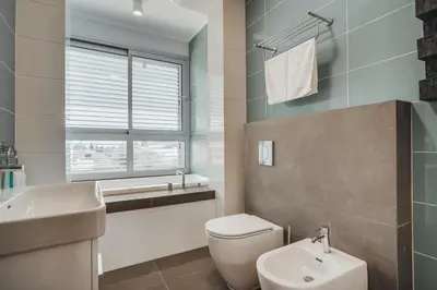 a bathroom with a toilet and a sink and a window at Stay in Style in Modern 3 Bedroom Villas Near Nissi Beach & Square in Ayia Napa
