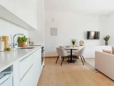 a kitchen and dining room with white cabinets and a table at Armonta Residences by BeCyprus in Limassol