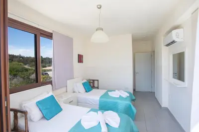 a bedroom with two beds and a large window at Villa Margarita in Protaras