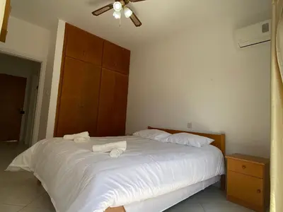 a bedroom with a white bed with two towels on it at 1 bedroom flat 200m from the beach in germasogia tourist area in Limassol