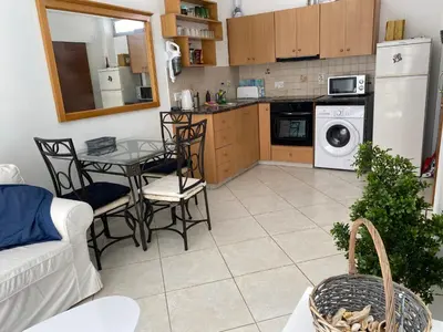 a kitchen with a table and chairs and a microwave at 1 bedroom flat 200m from the beach in germasogia tourist area in Limassol
