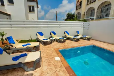 a patio with lounge chairs and a swimming pool at Nissi Villa Sotia in Ayia Napa
