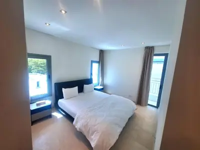 a bedroom with a white bed and two windows at Aphrodite Plaza in Larnaka