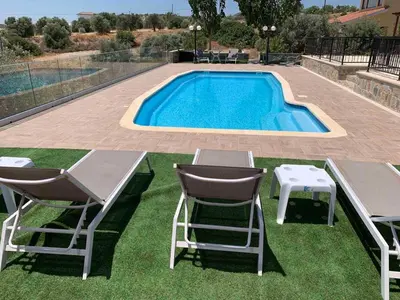 a swimming pool with two chairs and a table next to it at STUDIO in CAPTAINS HOUSE WITH A POOL in Limassol