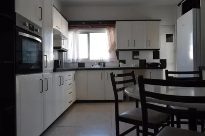 a kitchen with white cabinets and a table and chairs at MAMA'S FLAT - ΤΟ ΔΙΑΜΕΡΙΣΜΑ ΤΗΣ ΜΑΜΑΣ in Strovolos