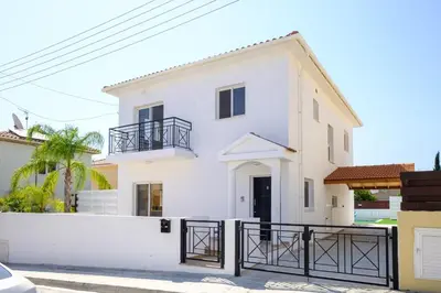 a white house with a black gate at Voroklini Villa with Pool in Larnaka
