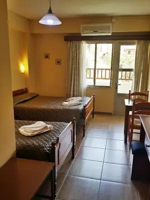 a hotel room with two beds and a table at Minaides Hotel in Kakopetria
